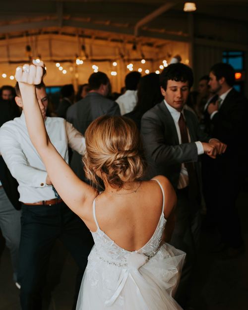 A guest dancing with an arm raised at a wedding reception.