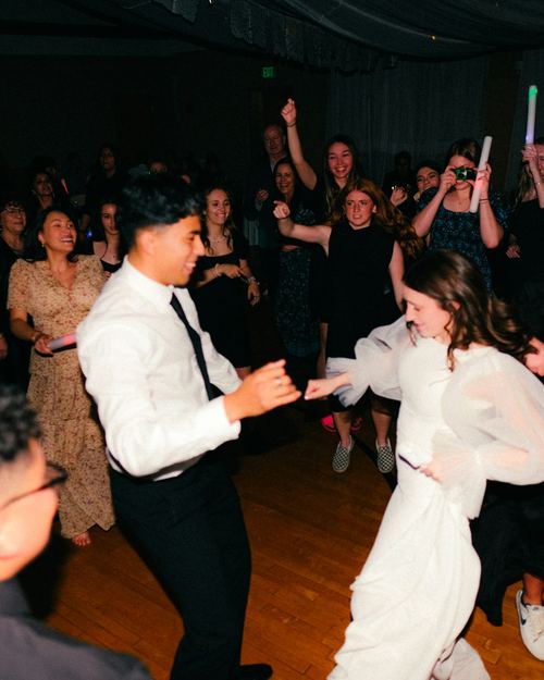 Guests of all ages dancing together on a packed floor.