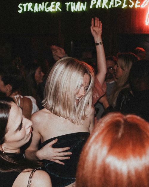 A crowded party dancing under neon light.